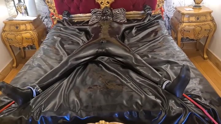 Latex-encased Woman Tied To Bed